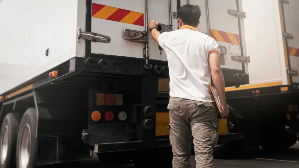 Homem verificando carga em um caminhão, focando na logística.