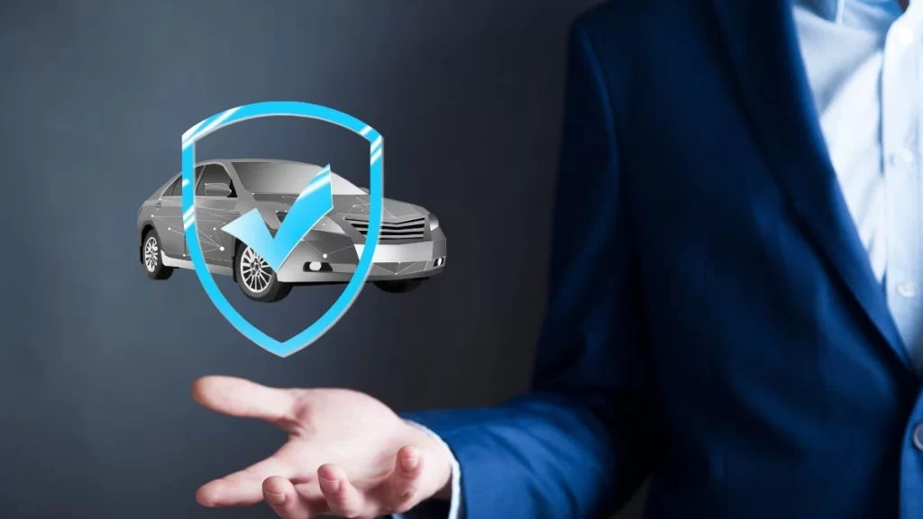 Homem segurando a palma da mão uma ilustração de carro com escudo e marca de verificação, símbolo da segurança automotiva.